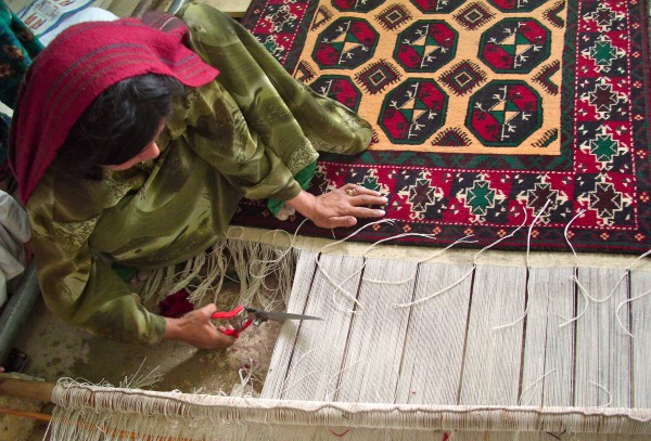 woman cutting Oriental Rug from loom